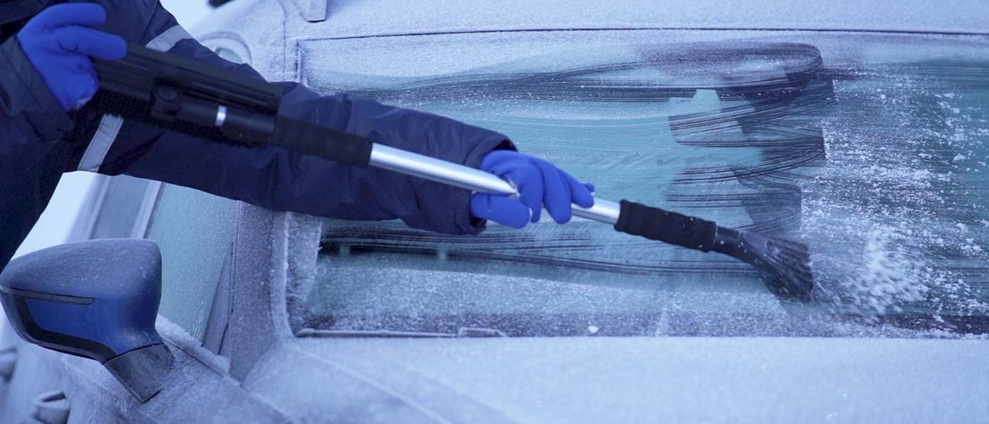 En person bruger en isskraber til at skrabe is af en frossen forrude.