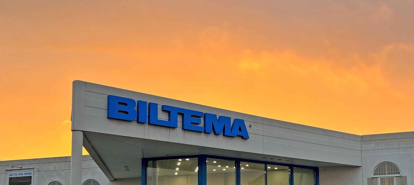 Biltema-varehus med blåt logo fotograferet i solnedgang med orangegul himmel.