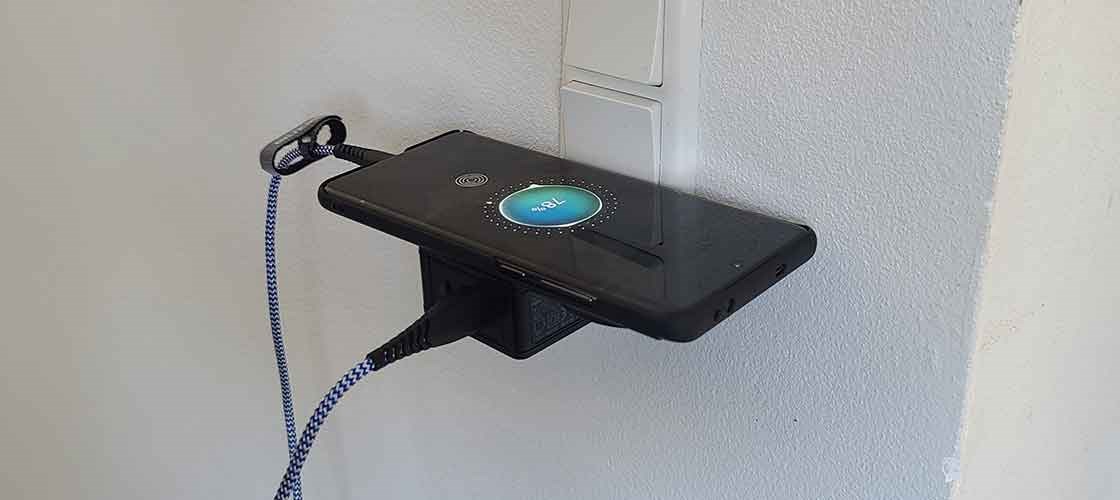 Smartphone oplades på vægmonteret laderstik med Biltema USB-kabel.