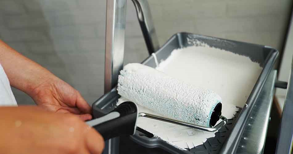 Biltema malerrulle og malerbakke i brug ved maling af væg indendørs.