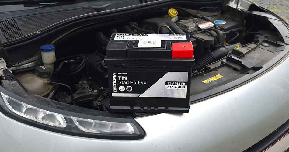 Car battery placed in the engine bay in front of other engine components.