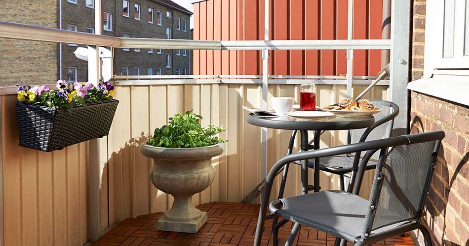 Balcony with table and chairs, served breakfast and flower boxes on the railing.