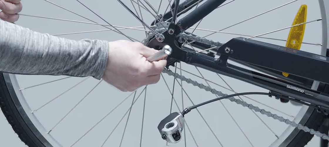 Installing and adjusting a bicycle wheel using Biltema tools while fitting hub gear and chain on a bike.