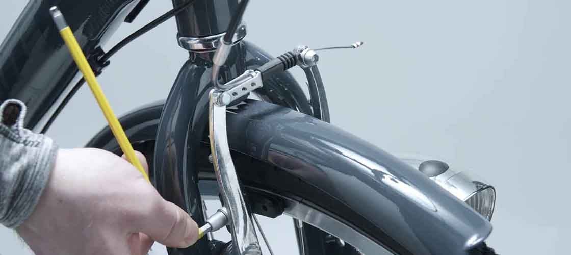 Adjusting bicycle brake using Biltema tools while installing front fender and brake arm on a bike.