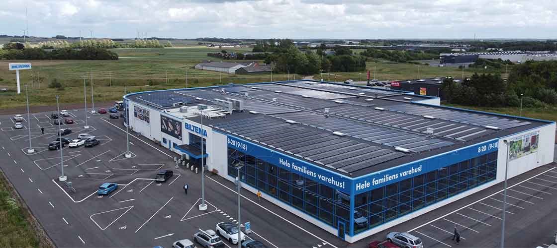 Biltema varehus med parkeringsplads og grønne arealer omkring fotograferet oppefra.