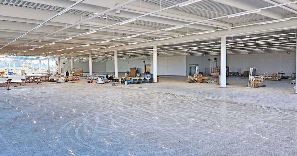 Stort, tomt butikslokale i Biltema Holstebro under opbygning med enkelte materialer og inventar langs væggene.